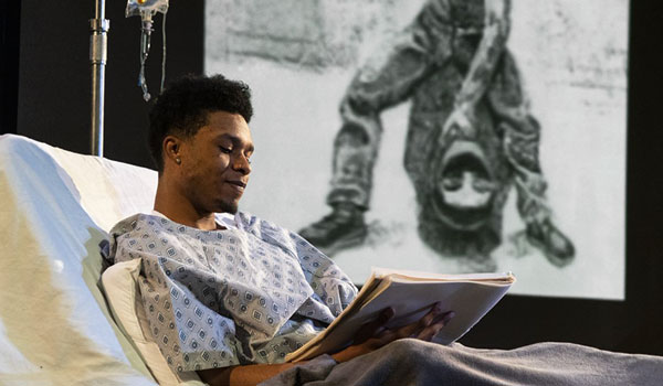 a young black man lay in a hospital bed, reading